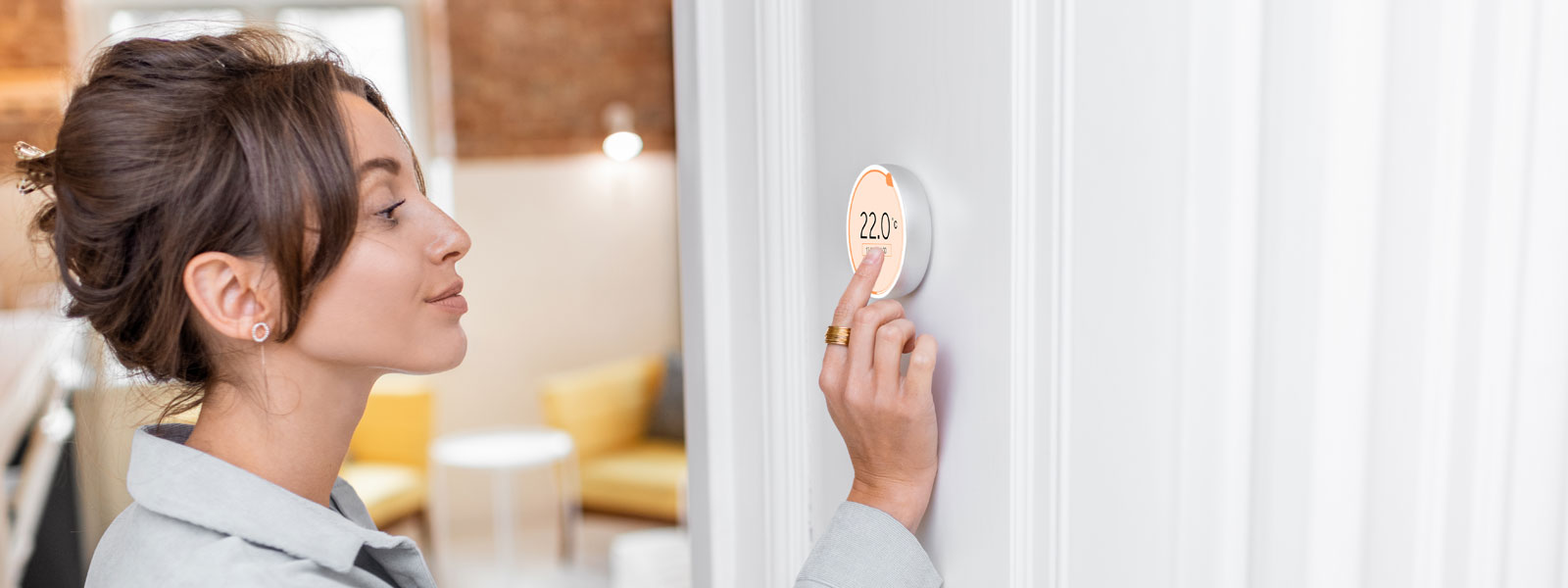 Woman Regulating Heating Temperature With A Smart Thermostat