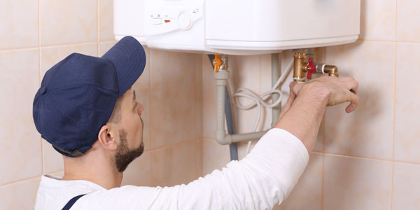 Plumber Installing Water Heater In Bathroom